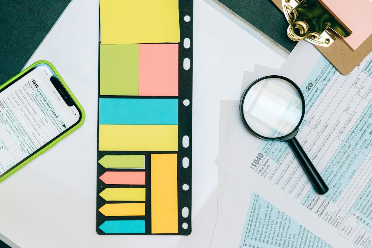 Colorful office supplies with smartphone and magnifying glass on tax forms. Perfect for business and financial themes.
